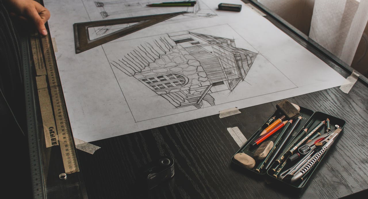 Close-up of an architectural sketch with drafting tools on a desk.